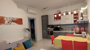 Et moderne køkken med spiseplads, en sofa med puder og et lille bord med kopper.