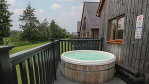 A wooden deck with a hot tub, a wooden fence, and a building with a window. - James Ville Marina Lodge 14 (Brigg)