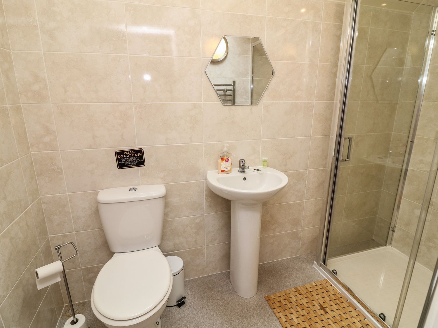 A bathroom with a toilet, sink, and glass shower enclosure.