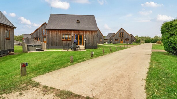 A rustic wooden building with a porch, a small outdoor seating area, and a clear sky. - James Ville Marina Lodge 14 (Brigg)