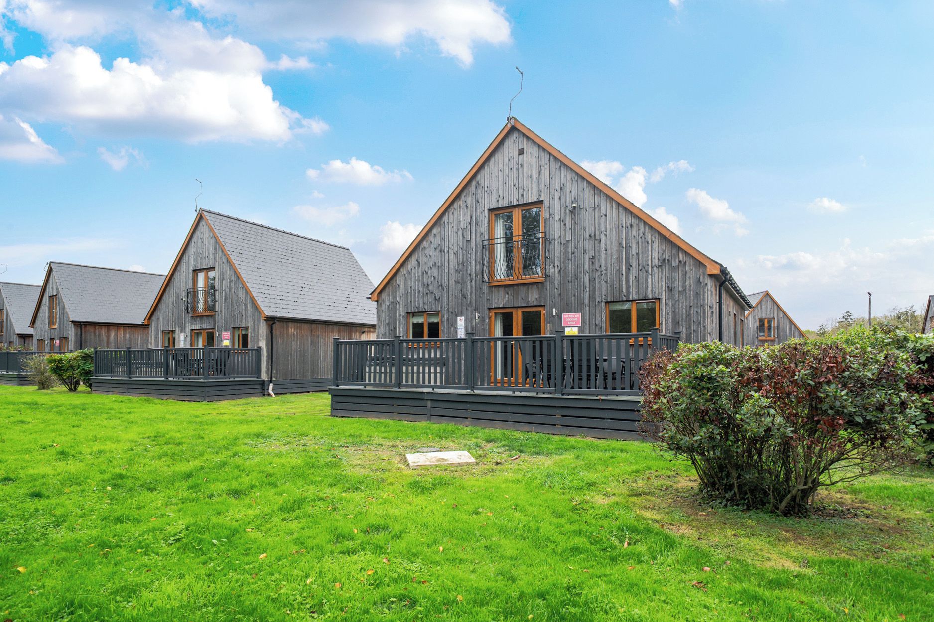 A row of wooden cabins with a grassy yard and a clear sky.