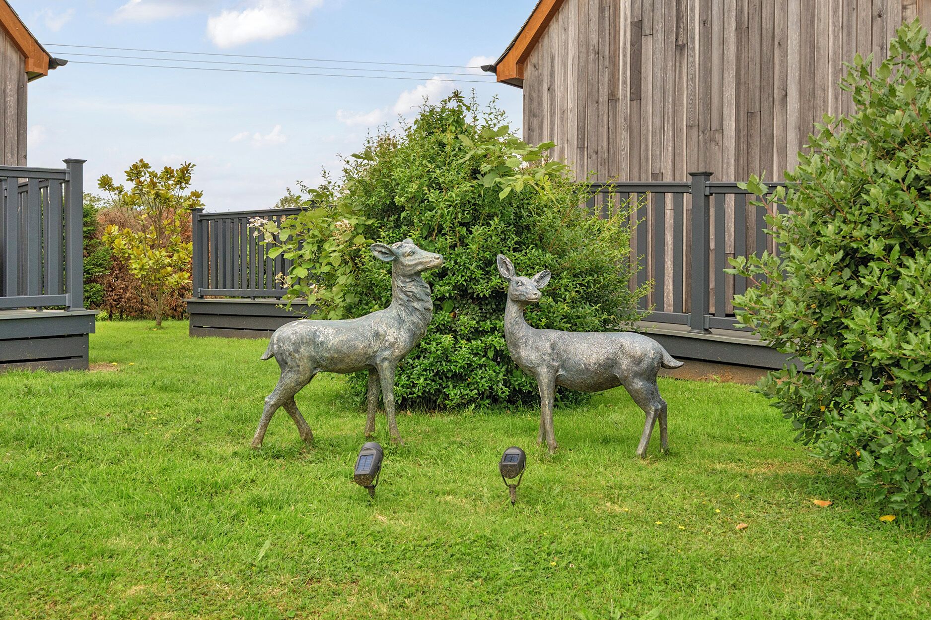 A fenced yard with two deer statues and a small bird statue.