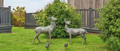 A fenced yard with two deer statues and a small bird statue.