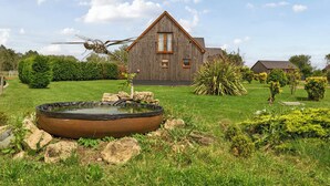 A wooden house with a triangular roof, a pond with rocks, and a garden with various plants. - James Ville Marina Lodge 14 (Brigg)
