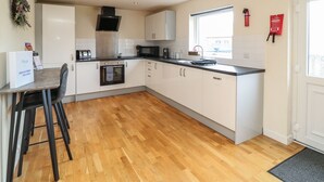 A modern kitchen with white cabinets, a black countertop, and a wooden floor. - James Ville Marina Lodge 14 (Brigg)