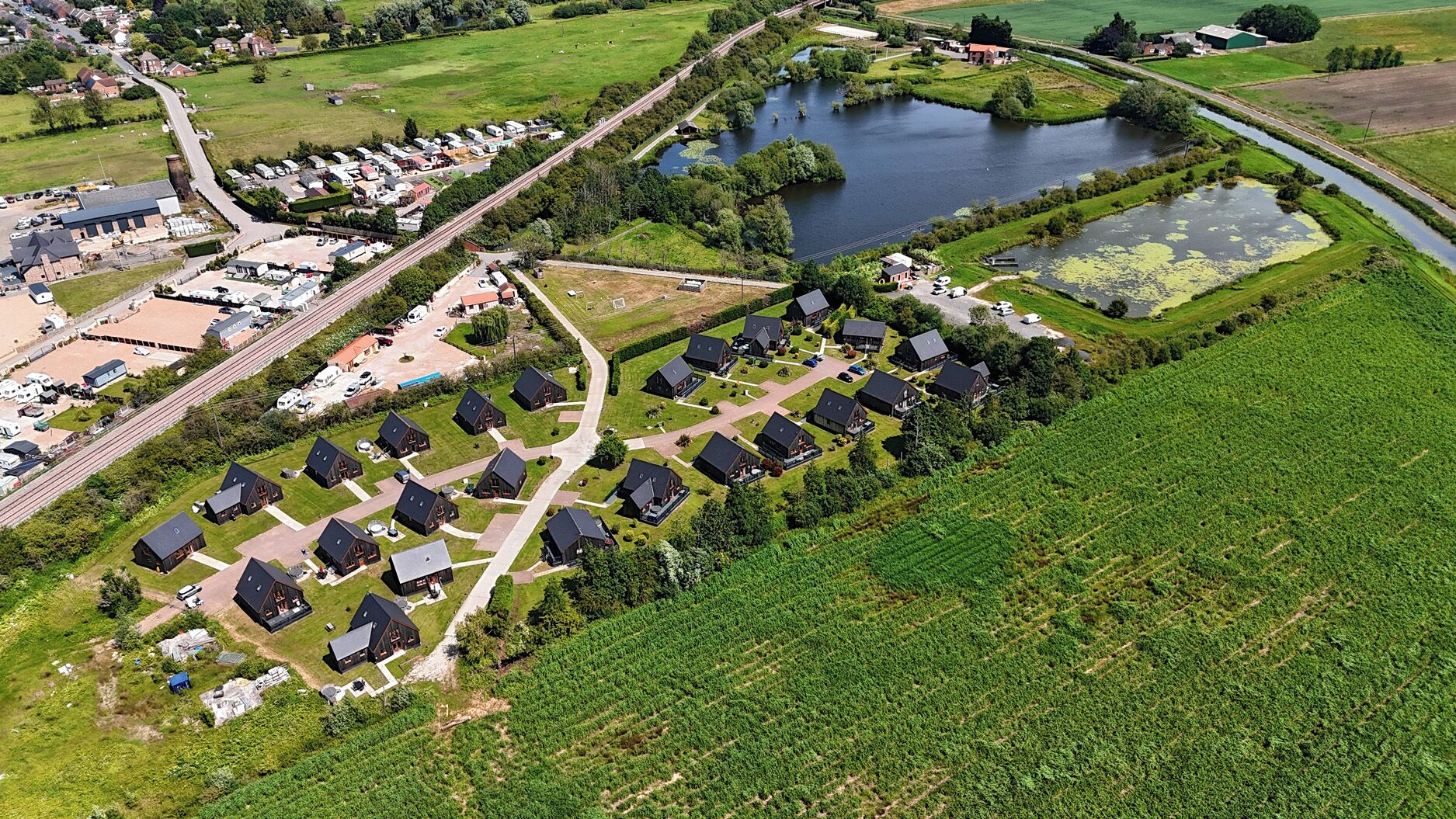 Vista aérea de una zona residencial con casas, un lago y una carretera.