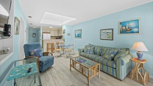 Una sala de estar con sofá, sillón, mesa de centro y comedor con sillas y una mesa.