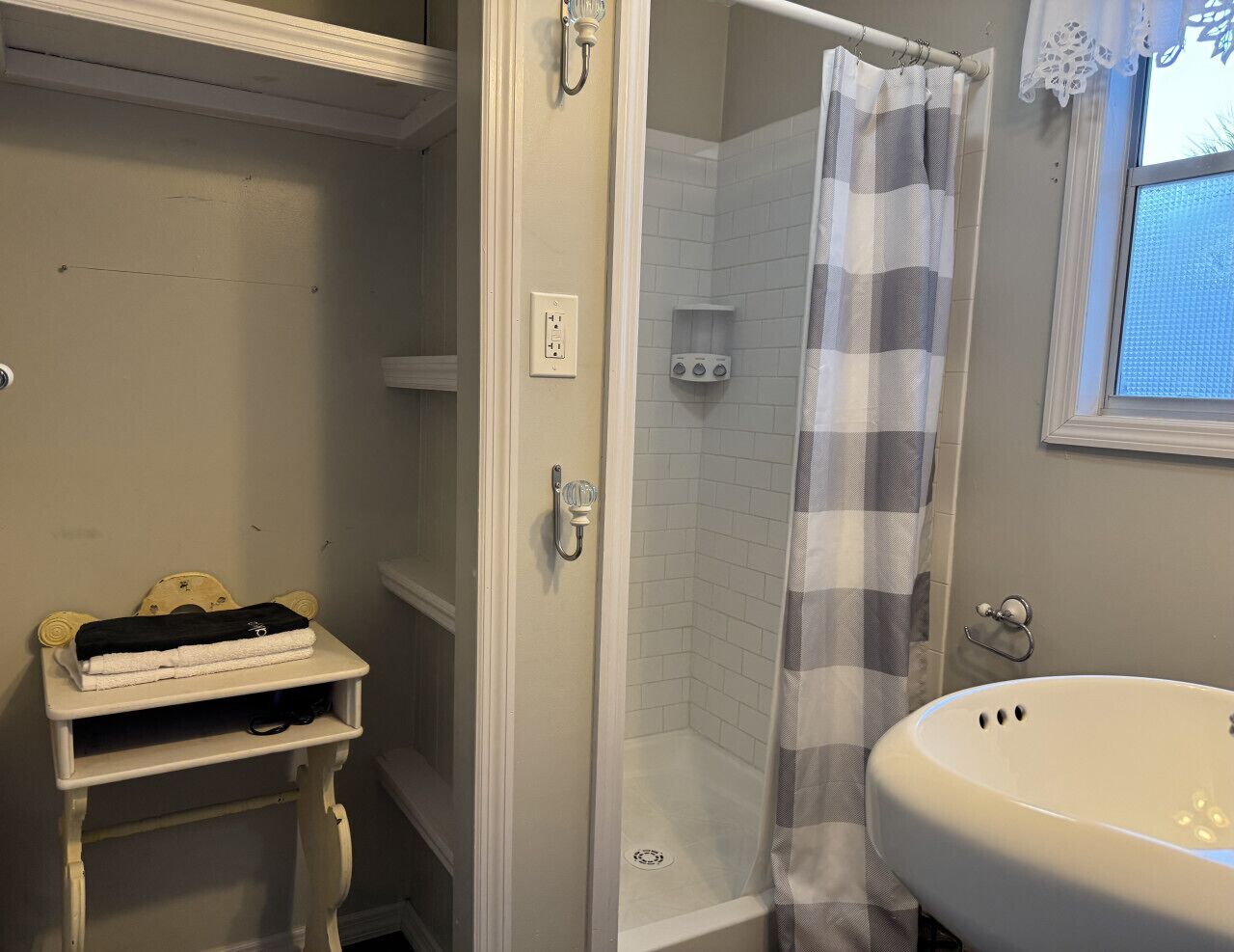 A bathroom with a white sink, a shower with a striped curtain, and a towel rack with towels.