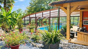 A covered outdoor area with a pool, potted plants, and a wooden deck.