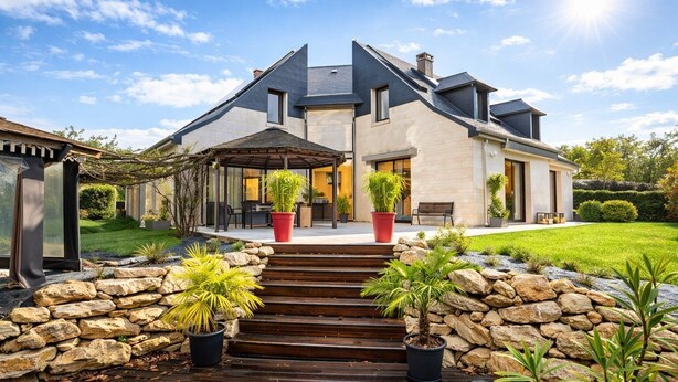 A modern house with a stone staircase, potted plants, and a well-maintained lawn.