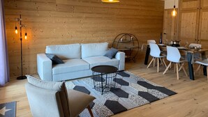Un salon moderne comprenant un canapé, des fauteuils, une table basse, un tapis et un coin repas avec une table et des chaises.
