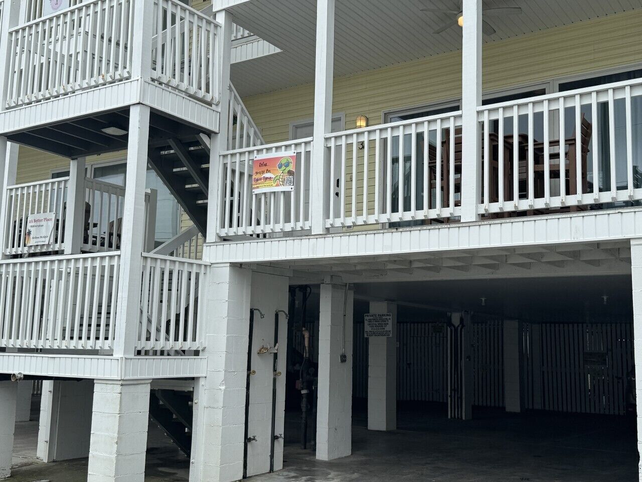 A multi-level building with a balcony, a staircase, and a private parking sign.