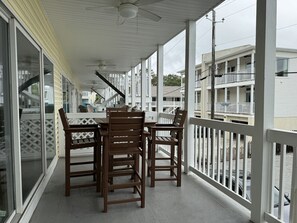 A covered balcony with a table and chairs, large windows, and a view of neighboring buildings. - Better Waves Ahead- 500 yds to the beach, Amenities Galore! (Tybee Island)