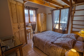 Een slaapkamer met een bed, een houten garderobe, een glazen tafel en een stoel.