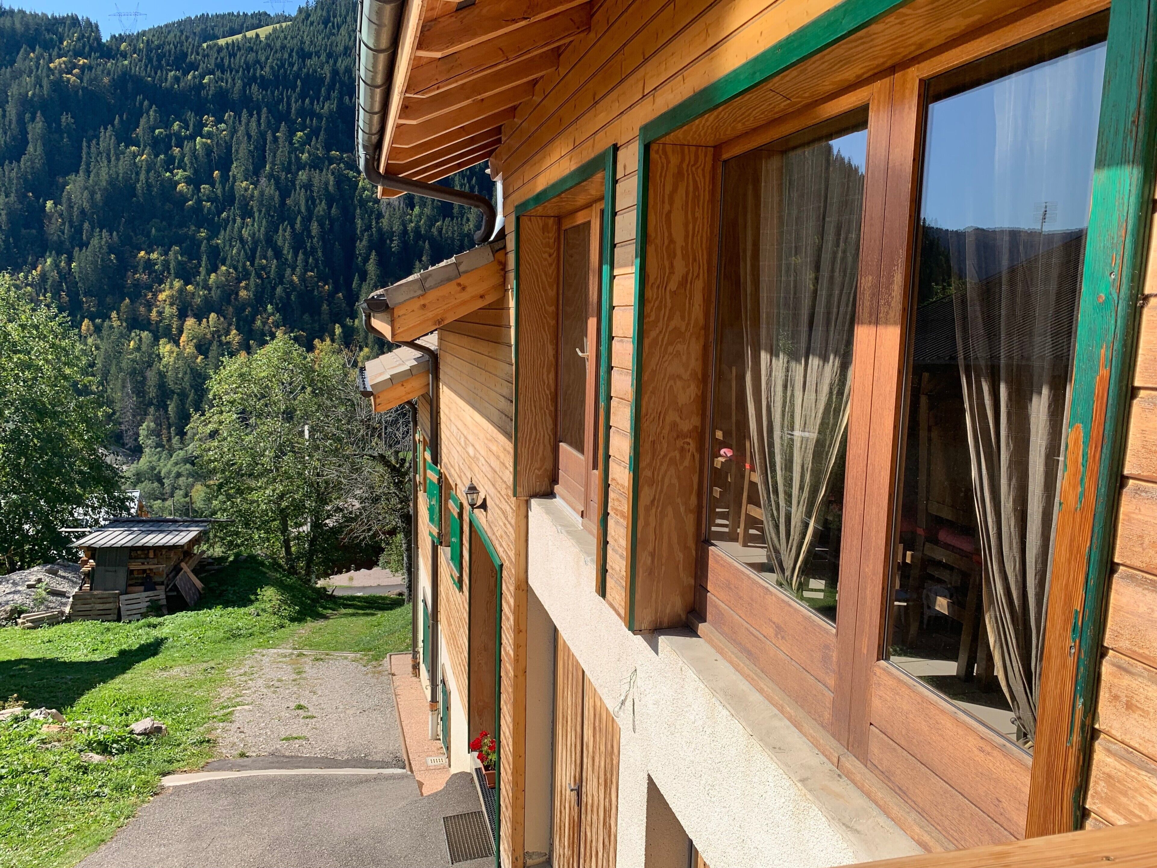 Une cabane en bois dotée de grandes fenêtres, d’un balcon et offrant une vue sur une montagne boisée.