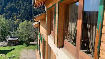 Une cabane en bois dotée de grandes fenêtres, d’un balcon et offrant une vue sur une montagne boisée.