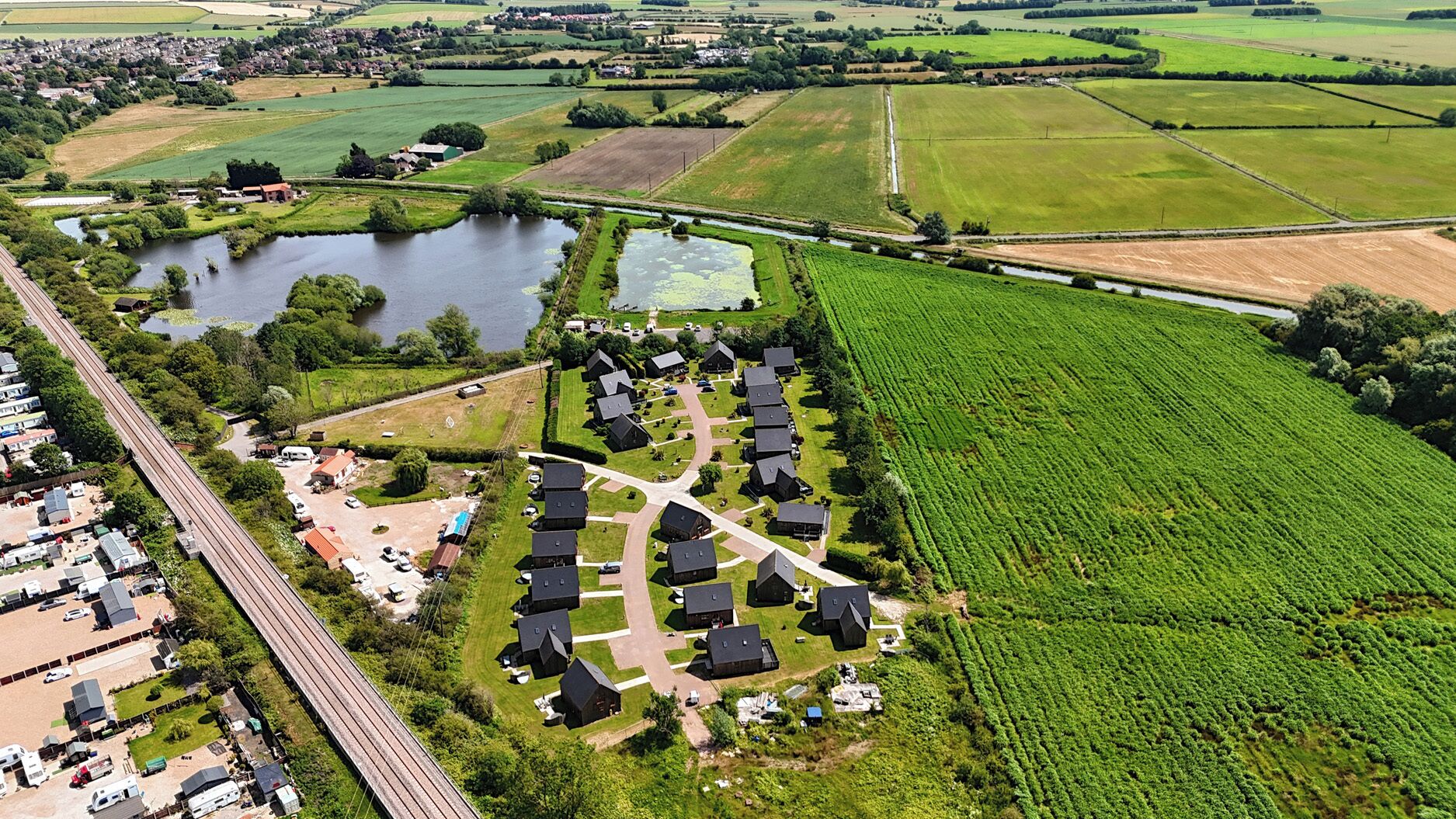An aerial view of a residential area with houses, a lake, and adjacent fields.