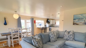A living room with a grey sofa, patterned cushions, a wooden dining table, and chairs. - Lodge 21 - Bluebell (Brigg)