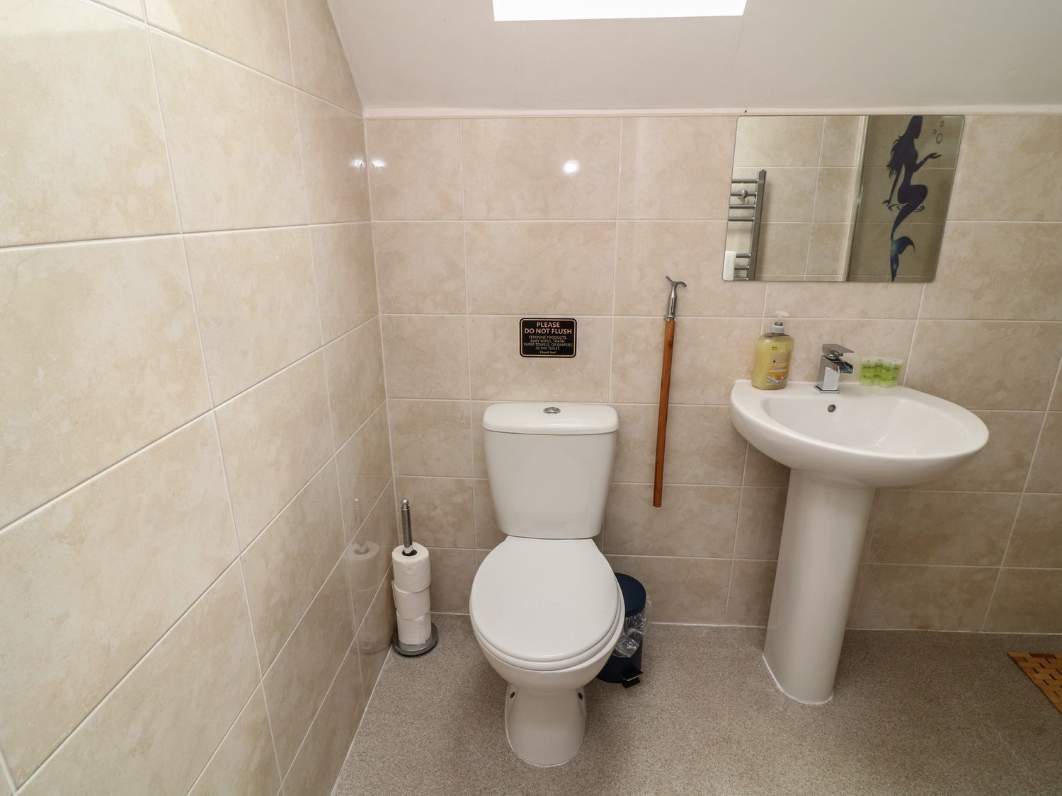 A small bathroom with a toilet, sink, and a mop.