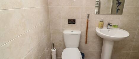 A small bathroom with a toilet, sink, and a mop.