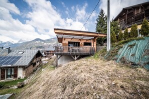 Eine moderne Holzjagdgenhütte mit Balkon, gelegen an einem Hang mit Bergblick.