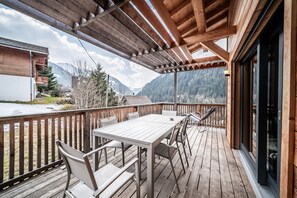 Eine Holzterrasse mit Tisch und Stühlen mit Blick auf eine gebirgige Landschaft.