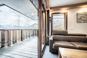 Un intérieur moderne avec une terrasse en bois, un canapé en cuir et une vue sur les montagnes.