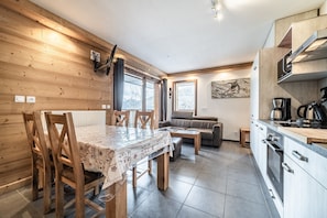 Une cuisine moderne avec des meubles en bois, une table à manger avec des chaises, un canapé et une machine à café.