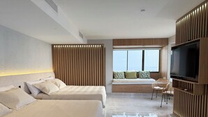 Habitación de hotel moderna con dos camas, zona de estar con vistas y un televisor de pantalla plana.