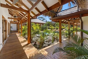 A wooden deck with a thatched roof, surrounded by tropical plants and a clear sky. - 5-suite boutique villa with a private pool in Playa Avellanas. 5 minutes from the ocean (Guanacaste Province)