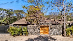 A stone house with a wooden door and a sloped roof. - 5-suite boutique villa with a private pool in Playa Avellanas. 5 minutes from the ocean (Guanacaste Province)
