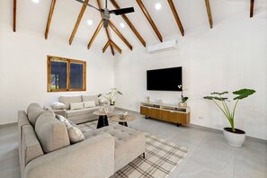 A modern living room with a sofa, coffee table, TV, and potted plants. - 5-suite boutique villa with a private pool in Playa Avellanas. 5 minutes from the ocean (Guanacaste Province)