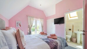 A bedroom with a bed, a TV, a bathroom with a toilet and sink, and a balcony. - Lodge 23 - Priscilla (Brigg)