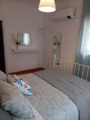 Ein Schlafzimmer mit einem Bett, einer Pendelleuchte, einem Spiegel und einer Klimaanlage.