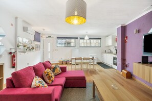 Een moderne woonkamer met een bank, een eettafel en een keuken op de achtergrond.