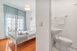 Een slaapkamer met een bed, nachtkastje, lamp en een raam met gordijnen.