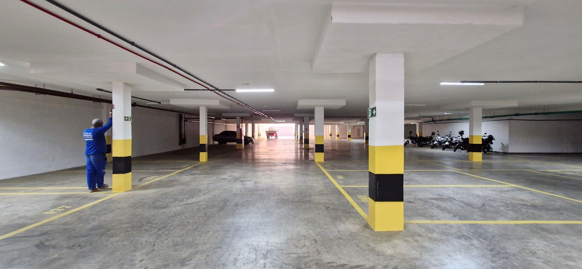 A multi-level parking garage with concrete floors and yellow and black striped pillars.