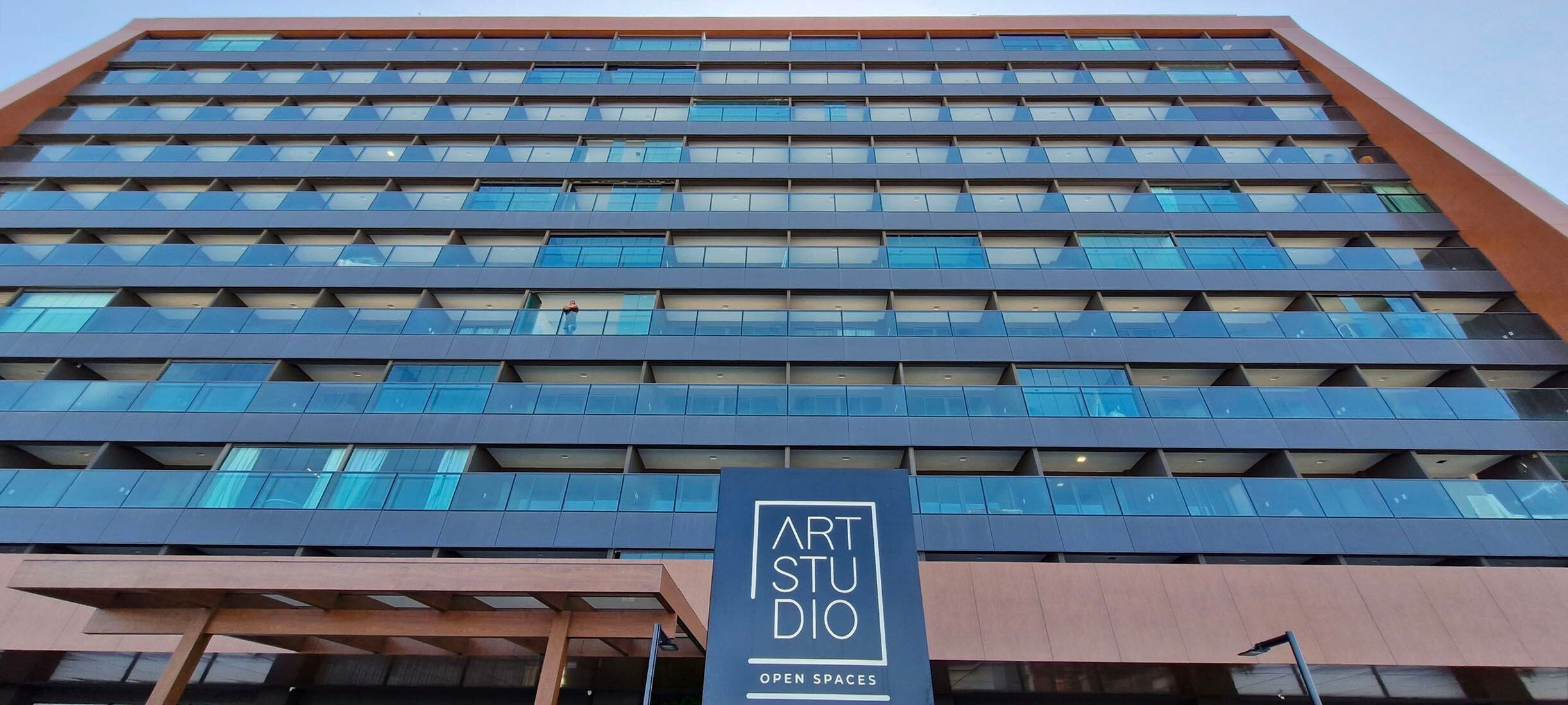 Un bâtiment moderne avec une enseigne indiquant : « ATELIER D’ART – ESPACES OUVERTS ».