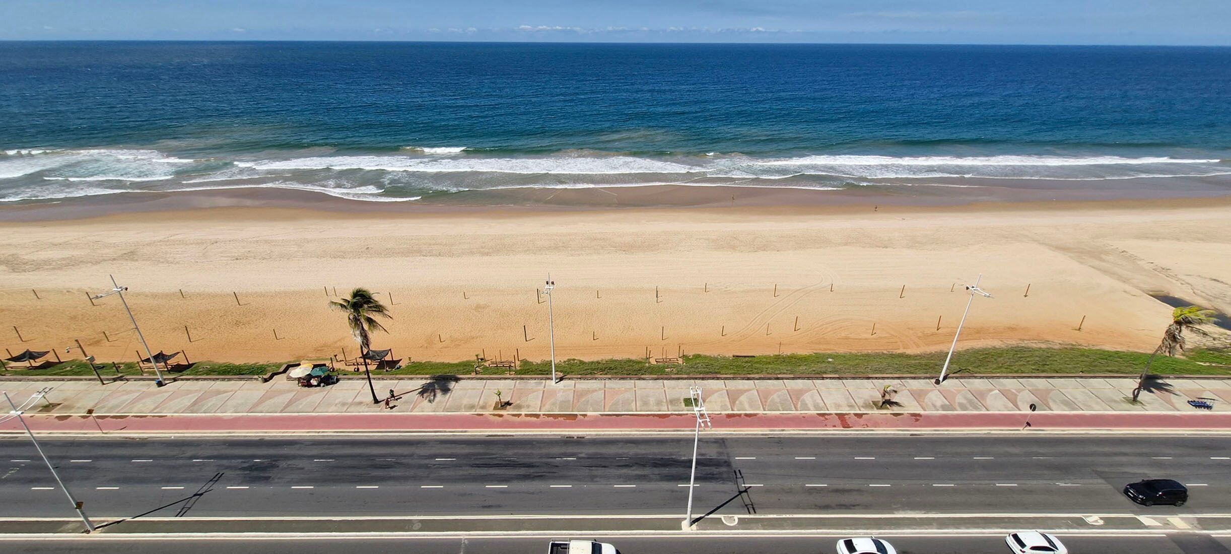 Una playa con una carretera al frente y el océano al fondo.
