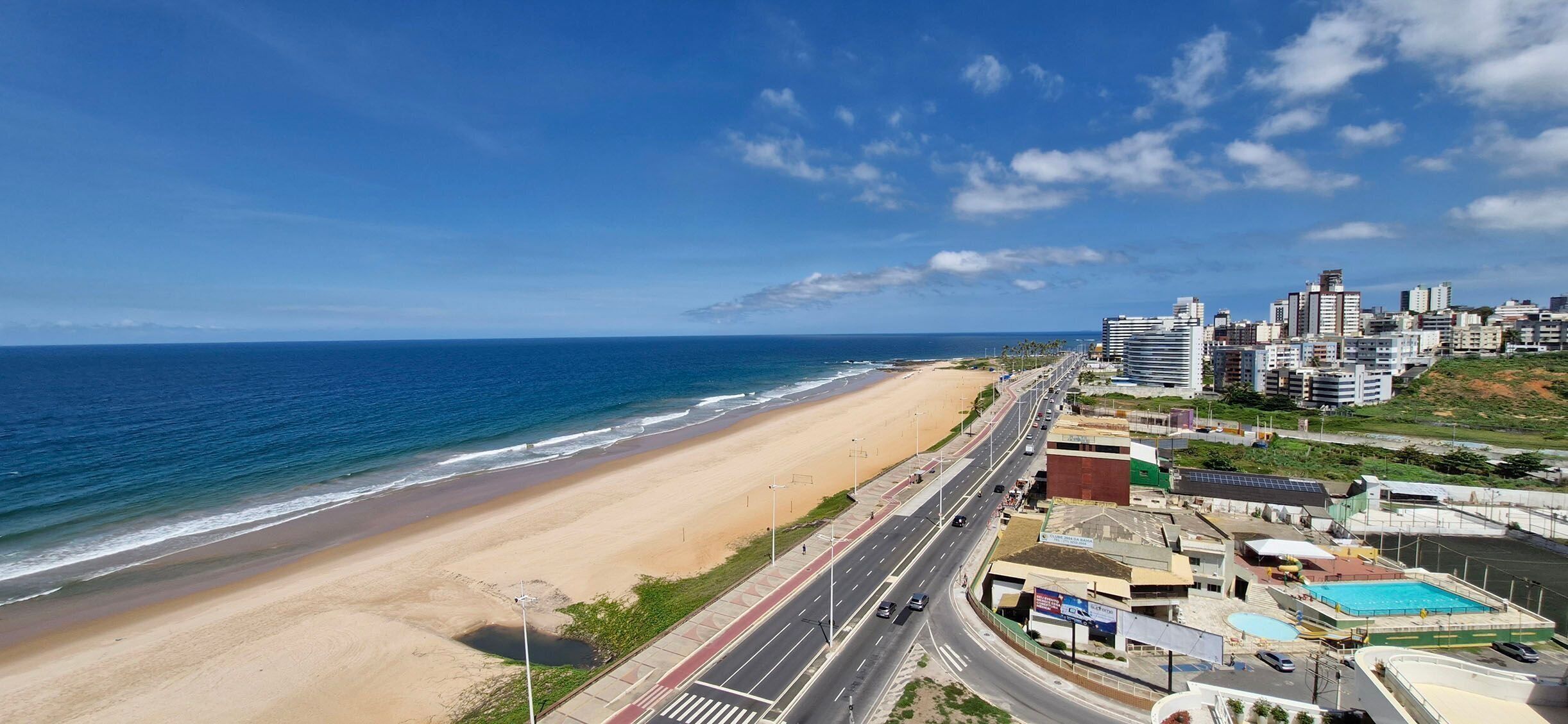 Un paysage urbain côtier avec une plage, des immeubles de grande hauteur et une route qui longe la côte.