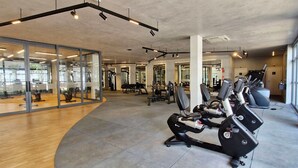 Ein modernes Fitnessstudio mit Laufbändern, Kraftgeräten und großen Fenstern.