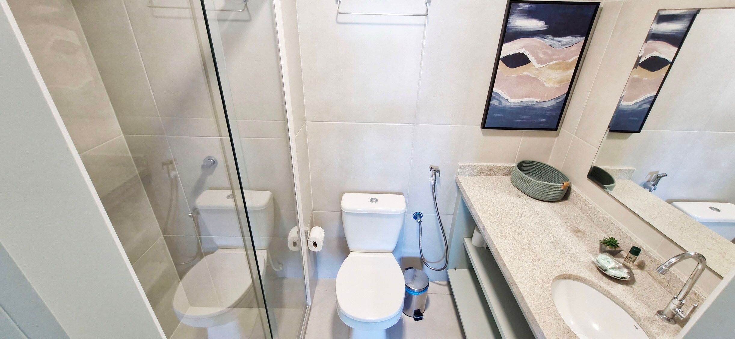 Une salle de bain moderne dotée d’une douche à parois de verre, de toilettes, d’un bidet et d’un meuble-lavabo avec un évier et un miroir.