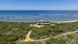 Una proprietà costiera con una casa moderna, un sentiero sterrato e vista sull'oceano.