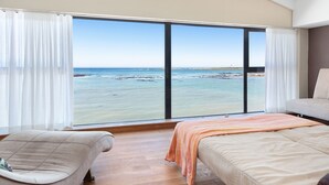 Una camera da letto con un'ampia finestra, due letti, un divano e vista mare.