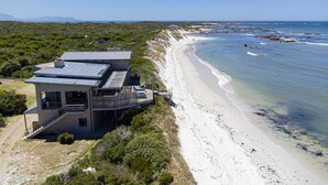 Una proprietà fronte mare con una casa moderna, completa di balcone e terrazza.
