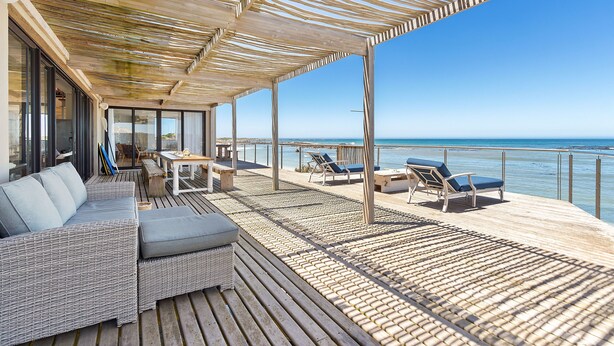 Un terrazzo con posti a sedere all'aperto, un divano e vista sul mare.