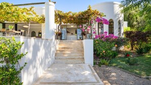 A white building with a covered staircase leading to a door, surrounded by greenery and flowering plants. - Riebeek-Kasteel Villa (Riebeek-Kasteel)