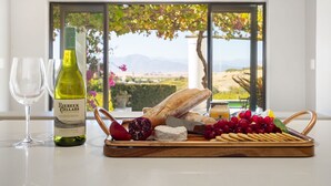 A table with a bottle of wine, a glass, a baguette, cheese, grapes, and a fruit bowl. - Riebeek-Kasteel Villa (Riebeek-Kasteel)