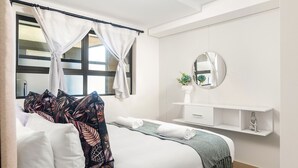 Ein Hotelzimmer mit einem Bett, einem Nachttisch, einem Spiegel und einem Vorhangfenster.