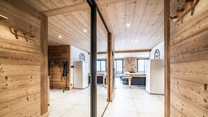 A wooden interior with a kitchen, dining area, and a visible door leading to another room. - Martonne - Le Haut Apartment: Mountain View, Private Terrace & Wi-Fi (Châtel)